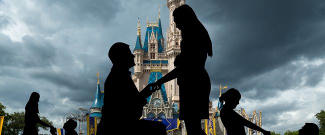 Multiple couples proposing marriage in front of Cinderella Castle