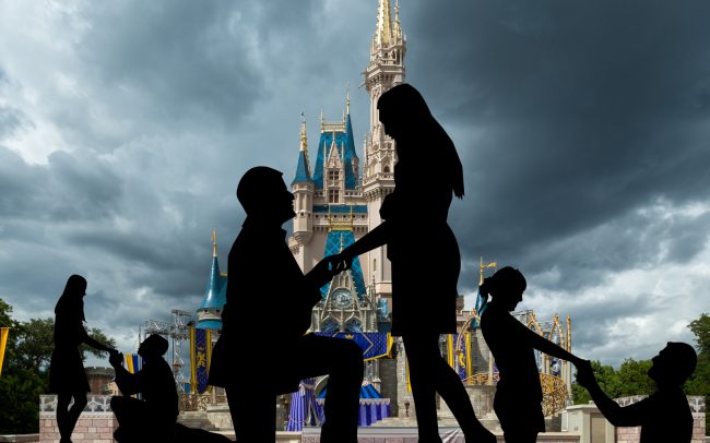 Multiple couples proposing marriage in front of Cinderella Castle